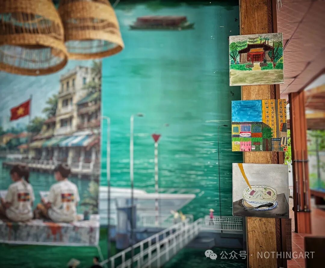 木柱上的三幅画分别描绘林木环绕的建筑、彩色城市楼房,以及一碗配有筷子的食物。