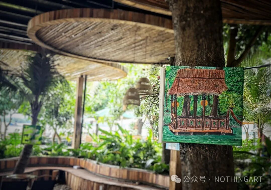 一幅绿意环绕的红顶亭子画作悬挂在展览空间的树干上。